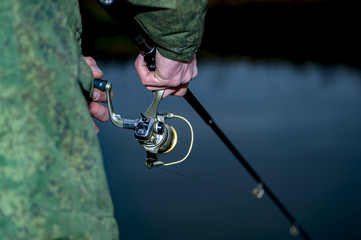 Male angler catches on a spinning fish in cold water in the offseason.