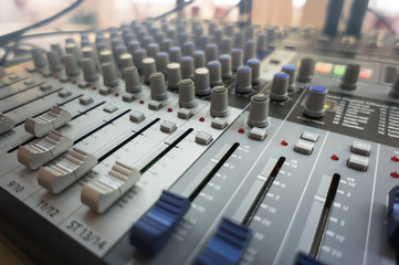 audio mixing console with faders and adjusting knobs