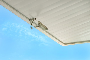 CCTV camera on a white roof, against the sky.