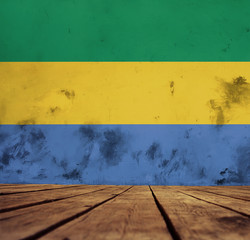The floor of planks and plastered wall with a painted Gabon flag.