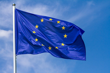 Flag of the European Union waving in the wind on flagpole against the sky with clouds on sunny day, close-up - obrazy, fototapety, plakaty