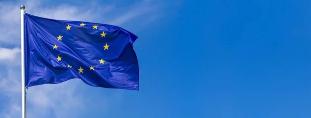 Fototapeten Flagge der Europäischen Union weht im Wind am Fahnenmast gegen den Himmel mit Wolken an sonnigen Tagen, Banner, Nahaufnahme © rustamank