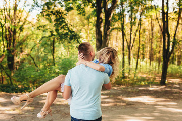 Fototapeta premium Young man holding girlfriend in his arms outdoors