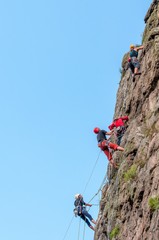 Rock climbing. A group of young rock climbers climb the vertical granite rock. Extreme sport.