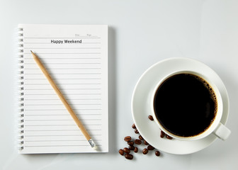 White cup of coffee morning on wooden table with notebook