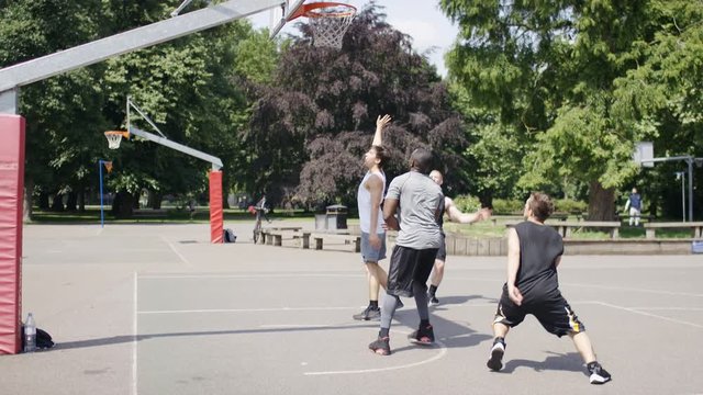 Group of young men playing basketball outdoors on a playground