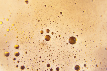 The foam of tasty fresh beer poured in a glass, shot from above.
