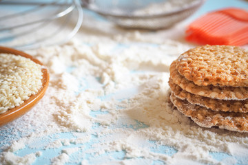 top view of product set for cooking cookies, kitchenware and several round cookies with sesame on a blue wooden table