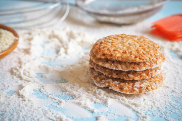 top view of product set for cooking cookies, kitchenware and several round cookies with sesame on a blue wooden table