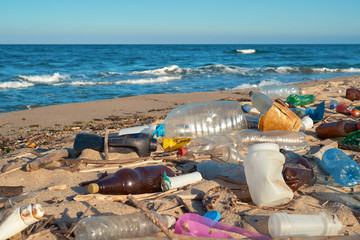 Spilled garbage on the beach of the big city. Empty used dirty plastic bottles. Dirty sea sandy...