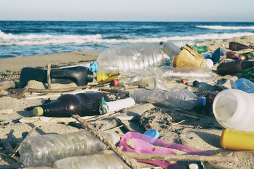 Spilled garbage on the beach of the big city. Empty used dirty plastic bottles. Dirty sea sandy...