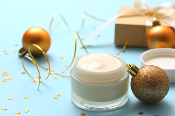 cosmetic cream and New Year decoration on a colored background. Christmas and New Year gifts.