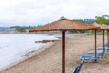 Bonita umbrella piling up in the beach. Portable lazy chairs diplay under the hut and facing the shoreline . resort amenities for guest and rentals concept.