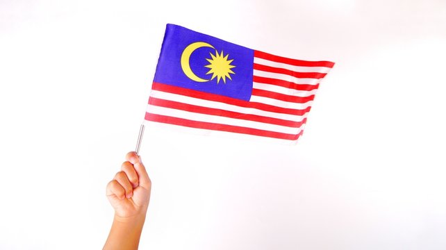 Hand Holding Malaysia Flag Isolated On White Background