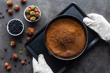 flat lay with baked homemade pie, fresh berries and oven cloth on dark grey tabletop