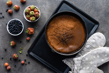 flat lay with baked homemade pie, fresh berries and oven cloth on dark grey tabletop