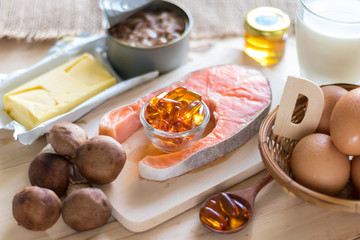 Fototapeta na wymiar Natural source of vitamin D in Salmon, eggs, mushroom, fortified milk, margarine, canned tuna and fish oil capsule on wooden texture and background, healthcare and supplemental concept