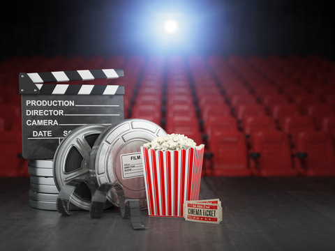 Cinema, movie or home video concept background. Film reels, clapper board  and pop corn in the theater movie cinema screen with empty seats.