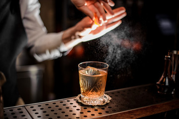 Fototapeta na wymiar Bartender making a fresh summer old fashioned cocktail with orange juice