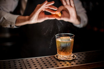 Bartender making a tasty old fashioned summer cocktail with orange juice