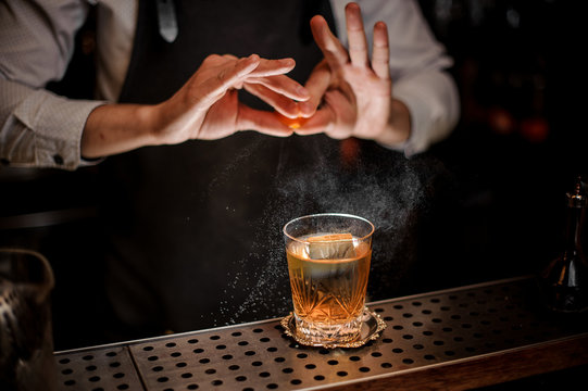 Barman making a fresh summer old fashioned cocktail with orange juice