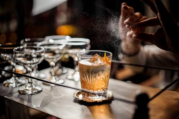 Deurstickers Cocktail Barman decoreert verse ouderwetse zomercocktail met ijs en sinaasappelschil