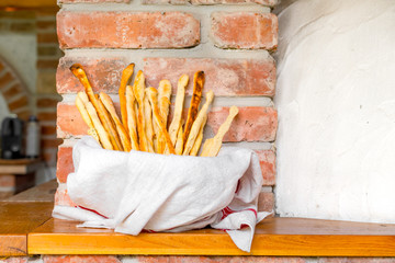 Rustic home-made breadsticks called grissini baked in a wood fired brick oven and served in a bowl covered with a white cloth 