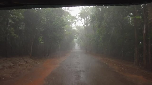 POV: Driving Down A Bumpy Forest Road On A Rainy Day During The Wet Season In Cambodia. Sitting In The Back Of A Motorbike Taxi And Speeding Down Concrete Path During An Intense Tropical Rainstorm.