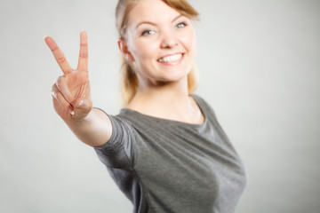 Cheerful female shows victory symbol.