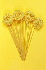 Close up of a raw dry italian pasta fettuccine on bright yellow background. Shooting with bold color.
