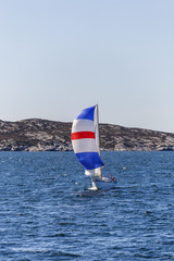 Fototapeta premium Sailboat with a colourful sail at a sea archipelago