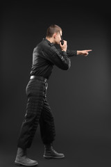 Male security guard using portable radio transmitter on dark background