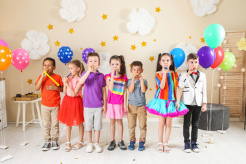 Fototapeta premium Adorable children with party blowers indoors. Birthday celebration