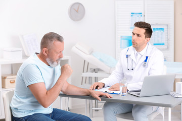 Obraz premium Coughing mature man visiting doctor at clinic