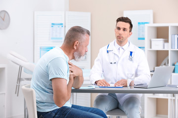 Obraz premium Coughing mature man visiting doctor at clinic
