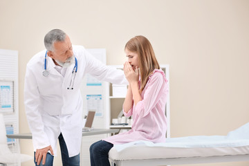 Obraz premium Coughing teenage girl visiting doctor at clinic