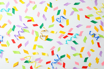 Colorful confetti and streamers on white background, top view
