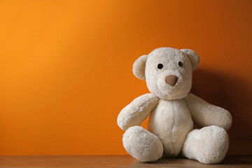 Abandoned teddy bear on table against color background. Time to visit child psychologist