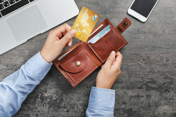 Woman holding leather wallet with credit cards on table, top view - obrazy, fototapety, plakaty
