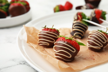 Plate with chocolate covered strawberries on table, closeup