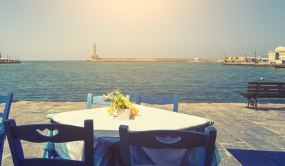 view from the taverns on waterfront of Chania lighthouse, sea, bench, bright Sunny day, the rays of the sun