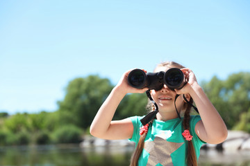 Little girl with binoculars outdoors. Summer camp