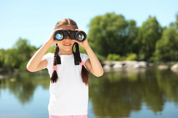 Little girl with binoculars outdoors. Summer camp