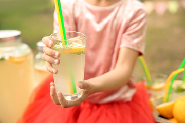 Little girl with natural lemonade outdoors, closeup