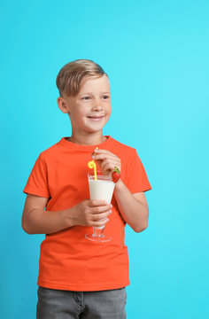 Little boy with glass of milk shake on color background