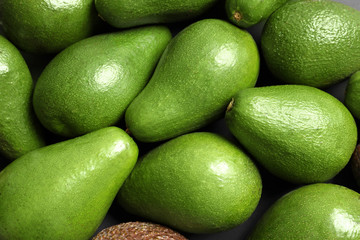 Many ripe fresh avocados as background