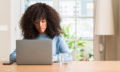 African american woman using laptop computer at home with a confident expression on smart face thinking serious
