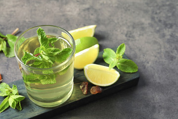 Glass with hot aromatic mint tea, fresh leaves and lime on table
