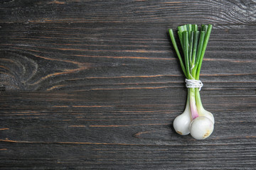 Tied fresh green onion on wooden table, top view