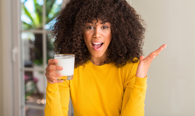 African american woman holding a glass of milk very happy and excited, winner expression...